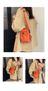 Détail du sac bandoulière orange en nylon avec fermeture à cordon et logo brodé