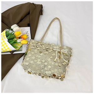 Detail of golden sequin tote bag featuring a decorative pearl bow charm and slim handle