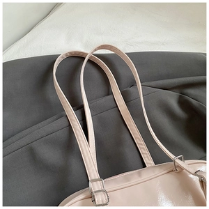 Close-up of pink patent leather bag showing handle stitching and silver metal hardware