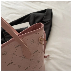 Detail of pink tote bag with litchi texture, cartoon prints and gold hardware rings