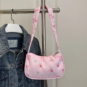 Pink crescent underarm bag with floral rose print and bow pattern on a hanger