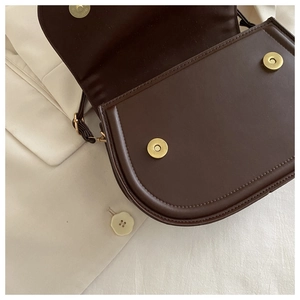 Detail of dark brown leather handbag showing gold magnetic closure and interior structure