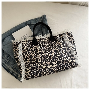 Detail of leopard print tote bag with white tassel fringe and black fabric handle