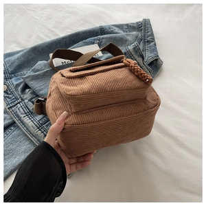 Detailed view of brown corduroy crossbody bag featuring a woven zipper pull and strap