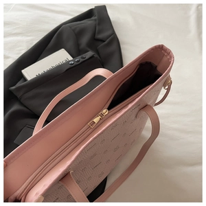 Top view of pink embossed tote bag with gold zipper and stylish pattern details