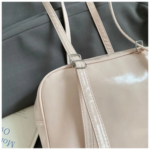 Close-up of glossy pink leather texture and silver square metal buckle on the shoulder bag