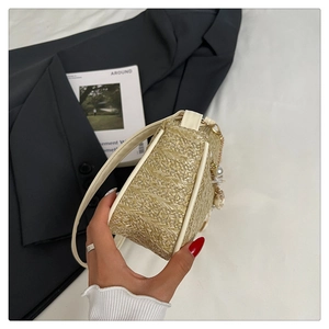Détail d'un sac en paille beige avec perles, charms floraux et anse en cuir crème