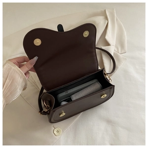 Top view of dark brown saddle bag interior showing storage space and magnetic buckle
