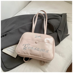 Detailed view of pink patent leather bag with silver butterfly embroidery and logo
