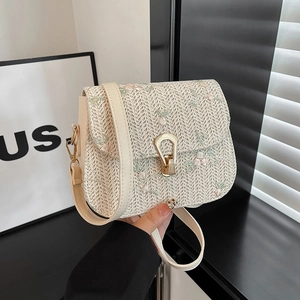 Straw shoulder bag with floral embroidery and gold pear-shaped lock in a hand-held view
