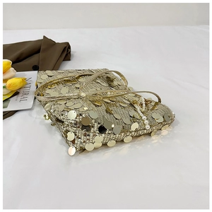 Detail of gold sequin evening bag featuring pearl chain and metallic shoulder strap