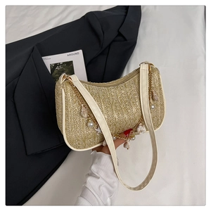 Détail d'un sac en paille tressée avec perles, breloques coquillages et chaîne dorée
