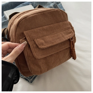 Detail view of brown corduroy crossbody bag featuring a front flap pocket and texture