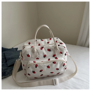 Détail du sac à lunch en velours côtelé avec imprimé fraise et bandoulière réglable