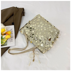 Detail of a golden sequin tote bag featuring a pearl bow pendant and matching strap