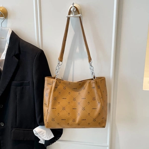 Brown tote bag with monogram pattern and chain strap styled with black blazer