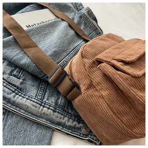 Detail of brown corduroy crossbody bag texture with adjustable strap and front pocket