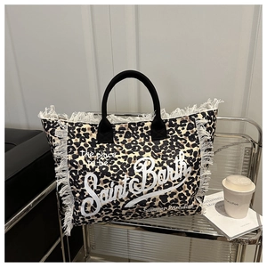 Close-up of leopard print canvas tote bag with white fringed edges and brand lettering