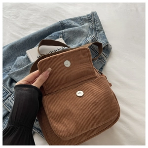 Brown corduroy crossbody bag detail showing magnetic snap closure and texture