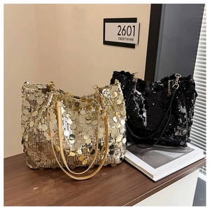 Detail of sequined gold and black tote bags with metallic chain straps on wooden table
