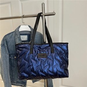 Blue quilted tote bag with metallic sheen, black straps and leather logo for women