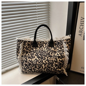 Detail of leopard print canvas tote bag with long white fringes and black handles