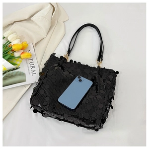 Close-up of black sequined tote bag with leather handles and size comparison to a phone