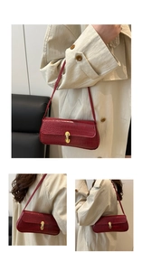 Detail of dark red crocodile embossed underarm bag with elegant gold metal lock