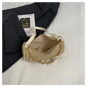 Détail du sac sous le bras en paille tressée avec breloque perle et lanière en cuir