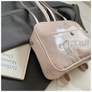 Detail of light pink patent leather mini backpack with silver bow embroidery and script logo