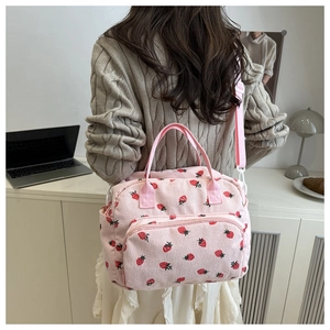 Pink corduroy bag with strawberry prints, showing side pockets and adjustable strap