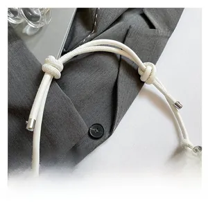 Detail of white leather shoulder strap with elegant knotted design and silver metal rings
