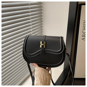 Detail view of the gold H-shaped metal buckle on a black leather saddle bag