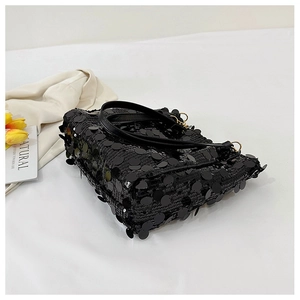 Detailed view of black sequins and gold metal rings on a luxury evening chain bag
