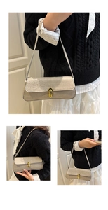 Detail of beige crocodile embossed baguette bag with elegant golden metal buckle clasp