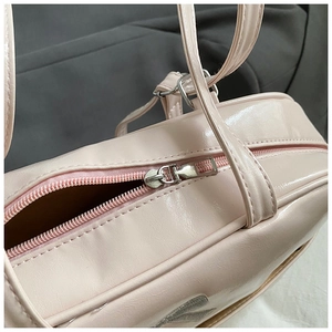 Detail of pink patent leather handbag with silver zipper and signature leopard logo