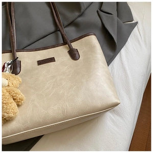 Detail of lychee textured tote bag with contrast brown straps and plush bear charm