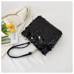 Detail of black sequin flap bag with metal chain strap on a white fashion background