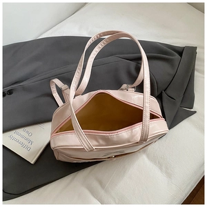 Detail of the pale pink patent leather shoulder bag with bow texture and zipper closure