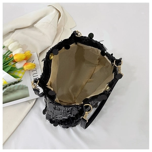 Close-up of black sequin handbag with magnetic gold clasp and smooth satin lining