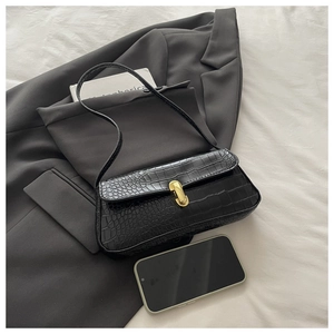 Close-up of black crocodile pattern baguette bag with vintage gold clasp on a blazer