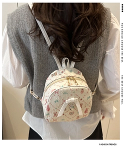 Detail of mini cream backpack with pink bear prints and 3D bow on model's back