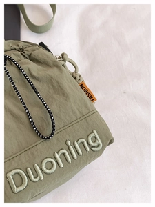 Detailed view of olive green nylon bag with Duoning embroidery and drawstring closure