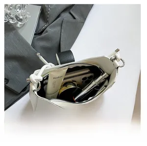 Internal view of white leather shoulder bag showing storage for phone and cosmetics