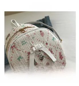 Close-up of white mini backpack with cartoon patterns and a large leather bow detail