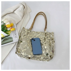 Macro shot of gold sequin tote bag with leather handle and smartphone for size scale