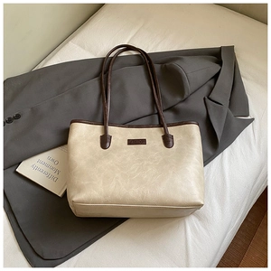 Detail of vintage cream tote bag with brown straps and FASHION label on white fabric