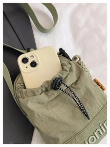 Close-up of olive green drawstring phone pouch with nylon texture and fashion label