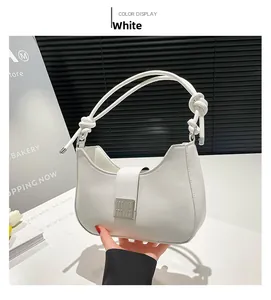 Detail of white leather crescent underarm bag with knot handle and metal buckle closure