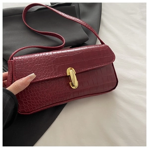 Close-up of burgundy crocodile pattern underarm bag with elegant gold metal buckle